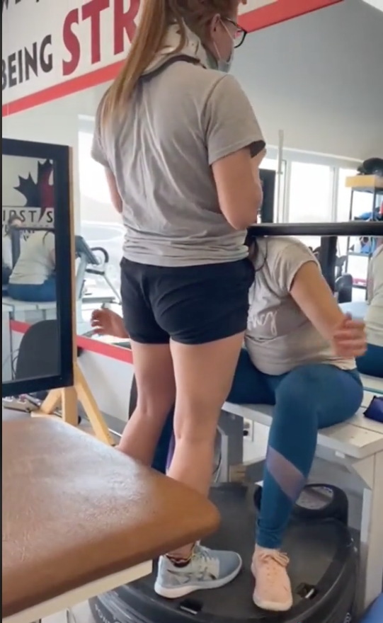 Brianna standing on Power PLate with coach