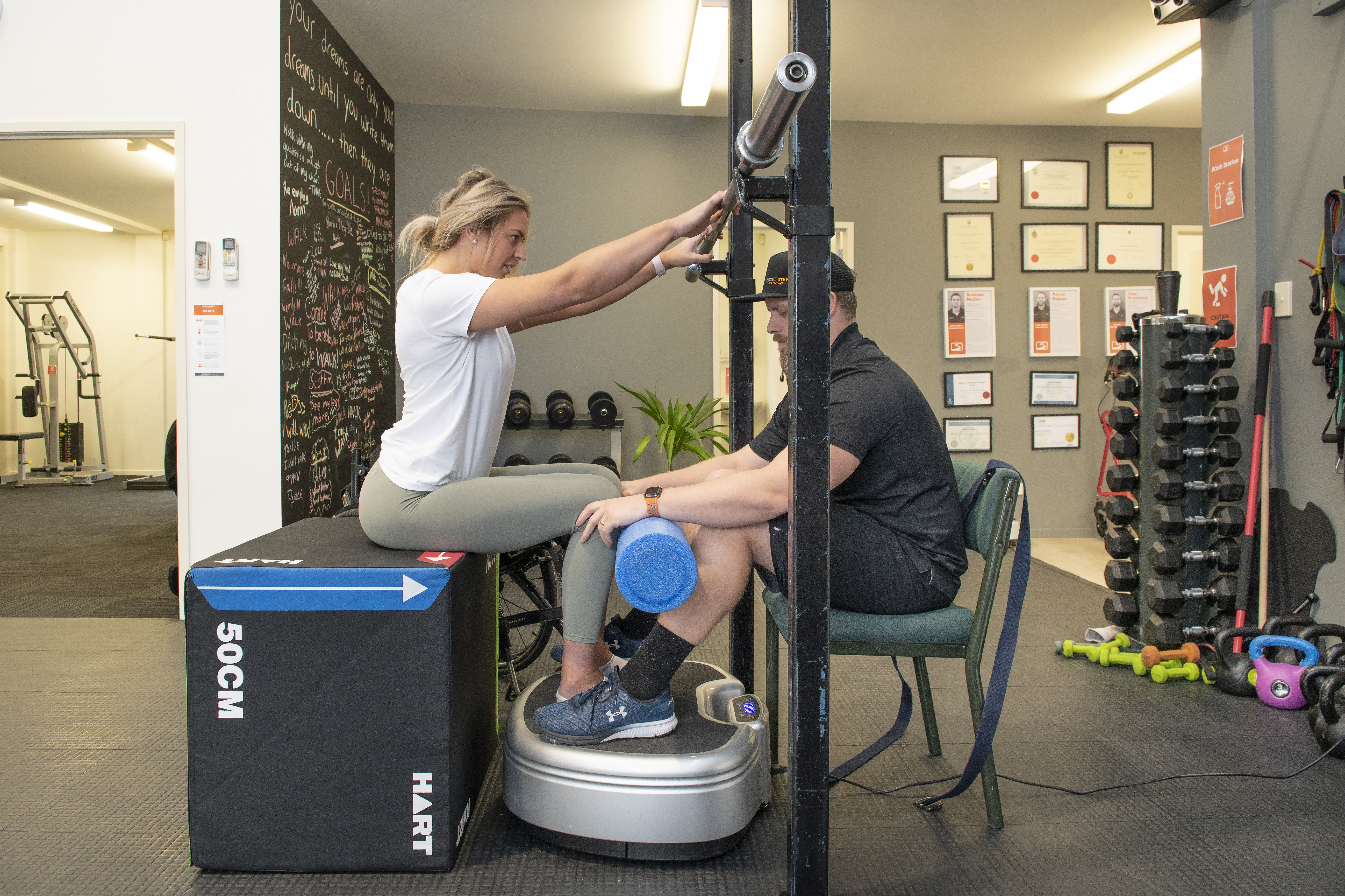 Casey sitting with feet on Power Plate while holding equipment